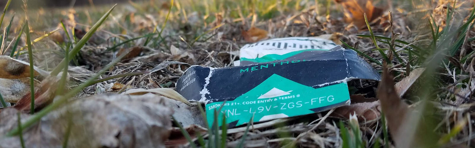 Crumpled menthol cigarette package in a field